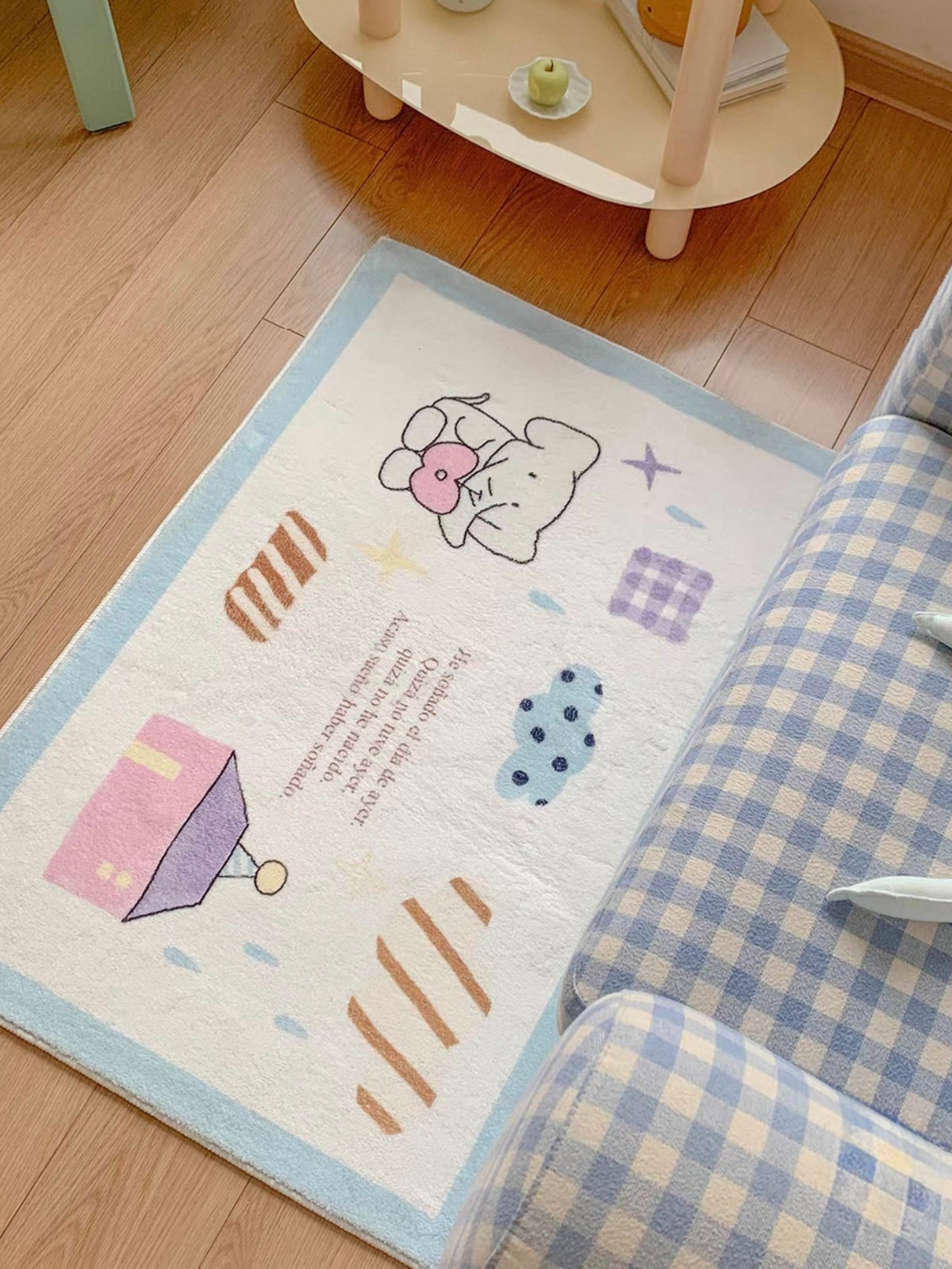 A blue bedroom rug lies beside an armchair, with an elephant holding a heart, a pink house and patterned marks.