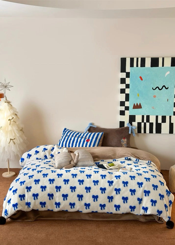 Bedroom with a bed covered in a white comforter with blue bows, striped pillow, and abstract painting on the wall.