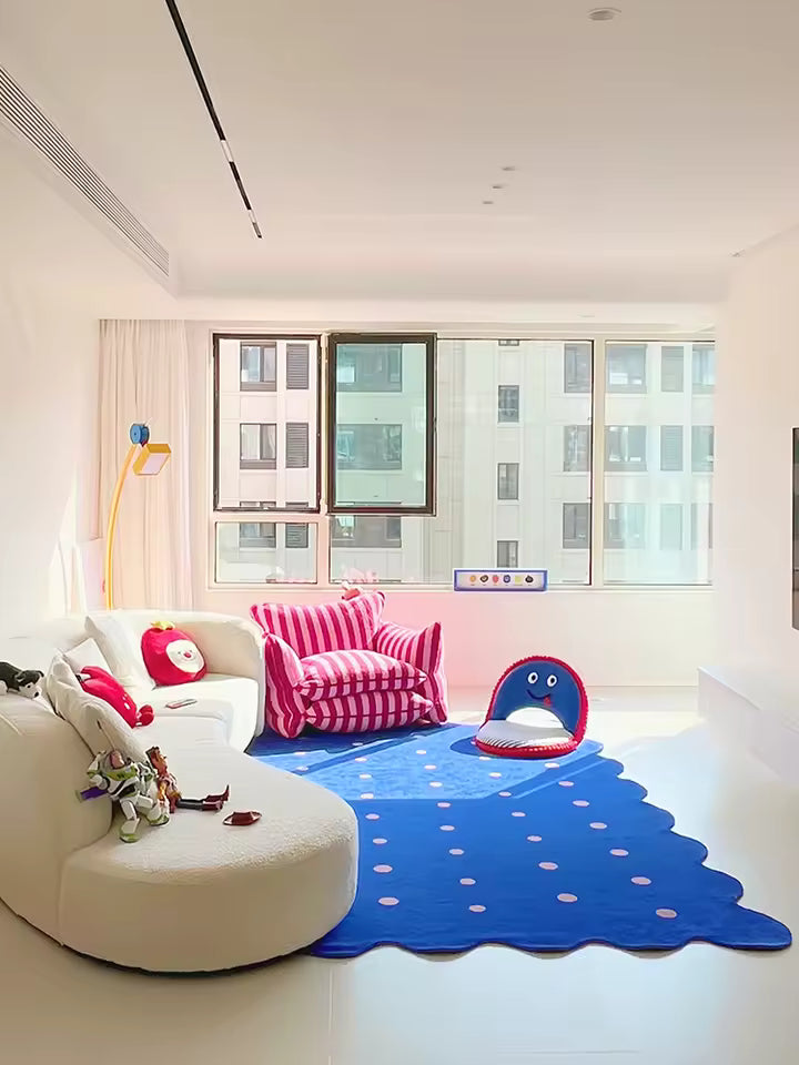 Modern living room with a blue rug, pink chair, and white sofa.