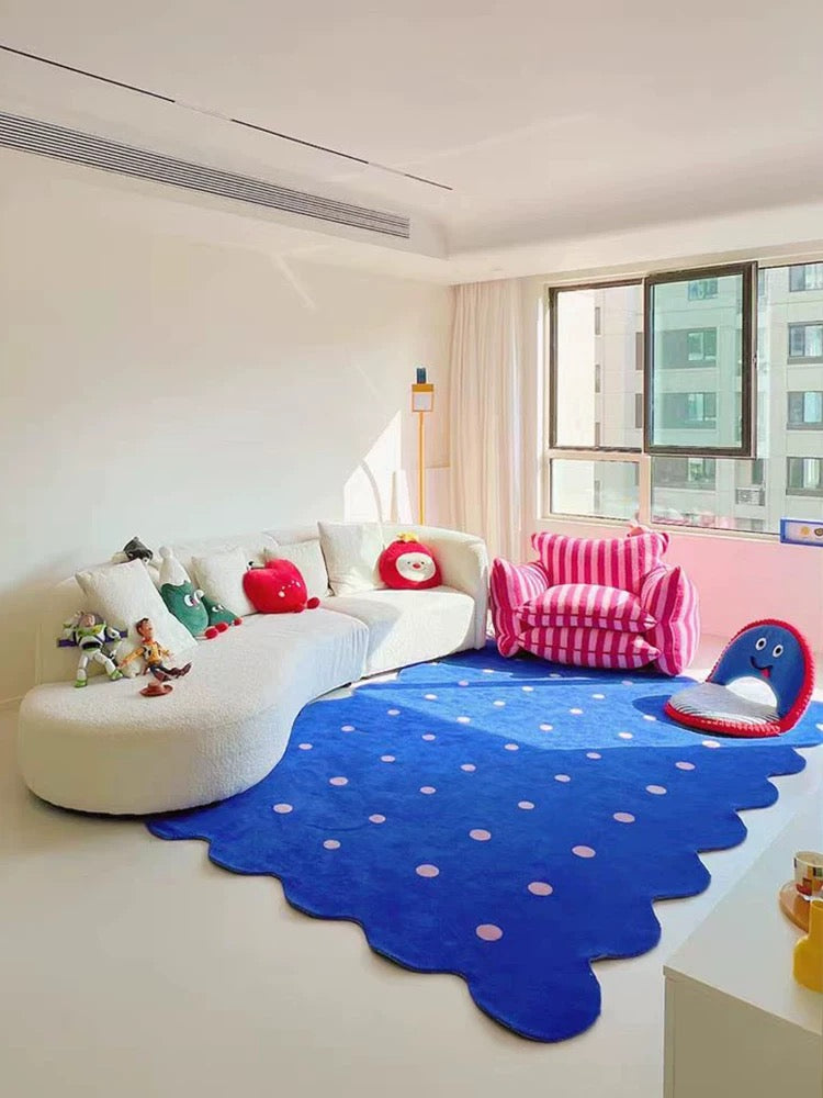 Children's playroom with a blue polka dot rug, white sofa, and pink chair.