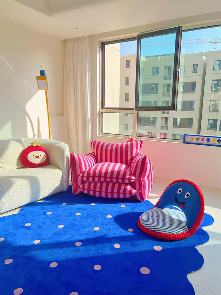 Children's room with a blue rug, pink chair, and colorful toys.