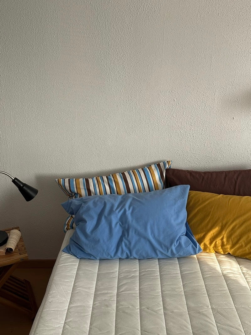 Solid blue and mustard pillowcases sit in front of mocha and striped designs.