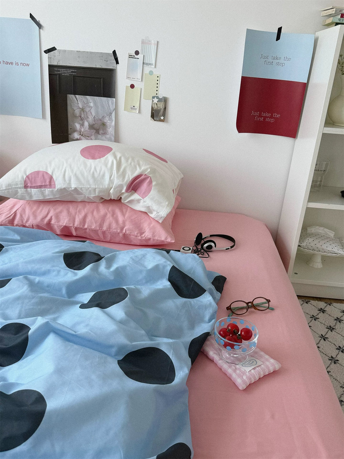 A pink dotted cream pillowcase rests on a plain pink pillowcase above the blue dotted cover.