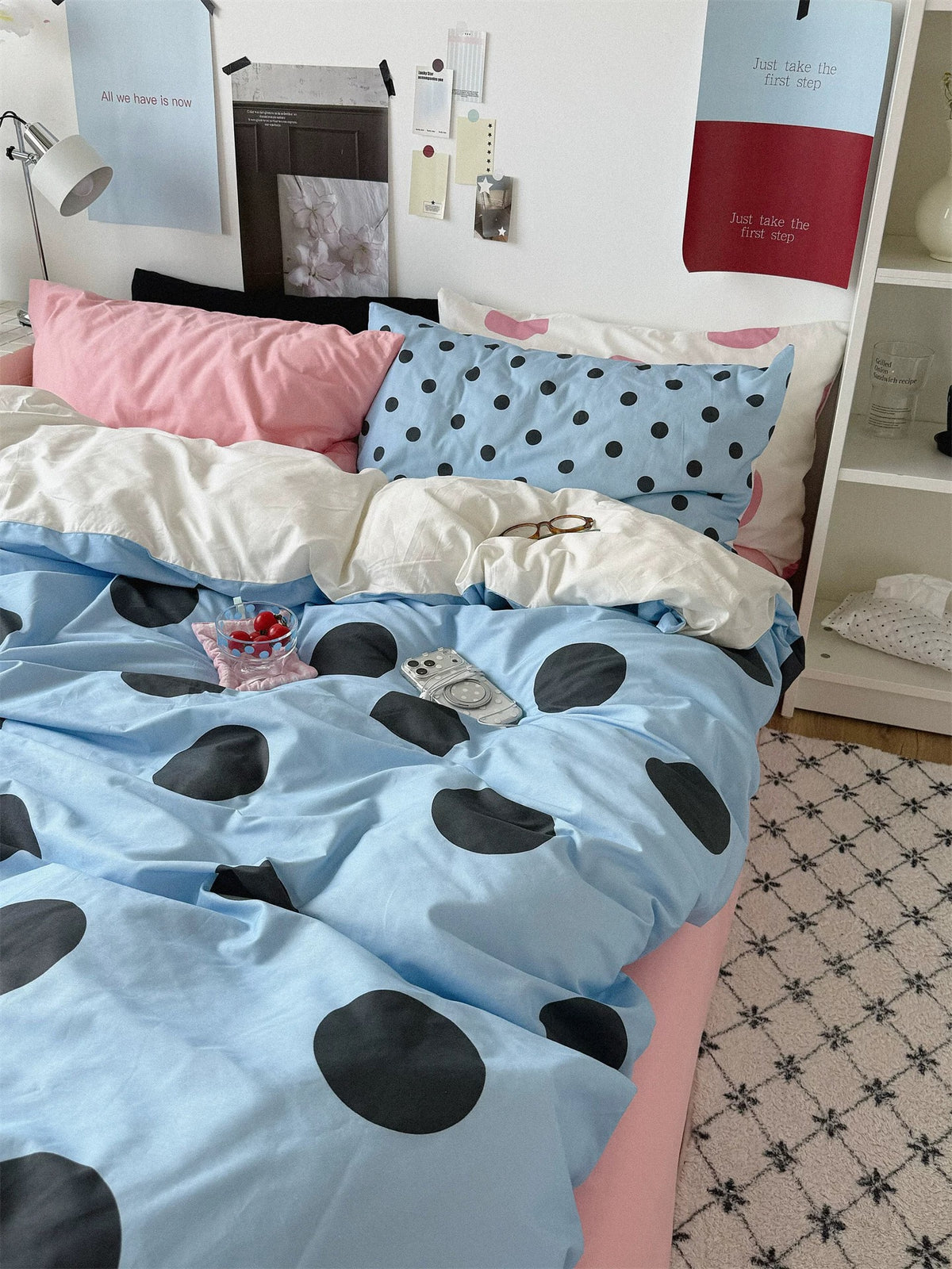 The blue dotted cover stretches toward the foot of the bed, with a strip of pink sheet visible on the right.