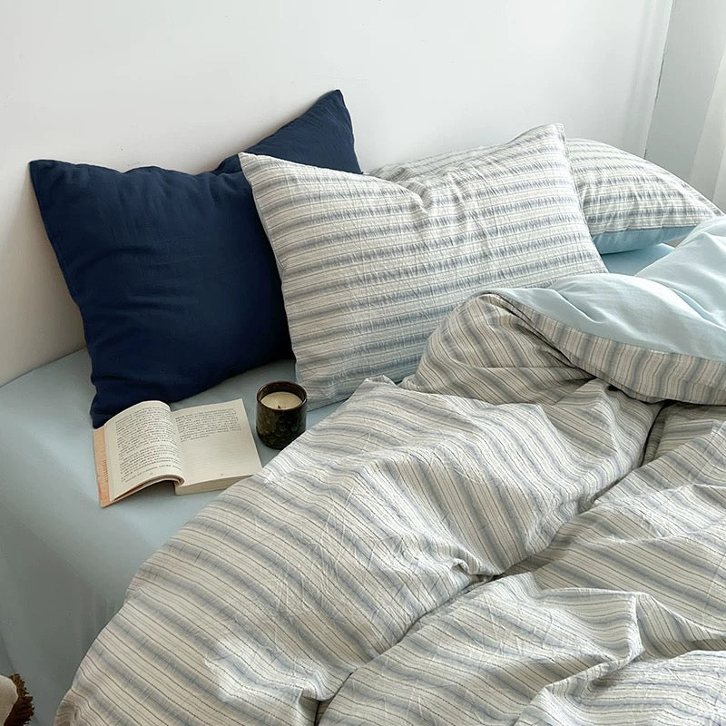 Reversible duvet cover flipped to show its solid seafoam blue side on a made bed