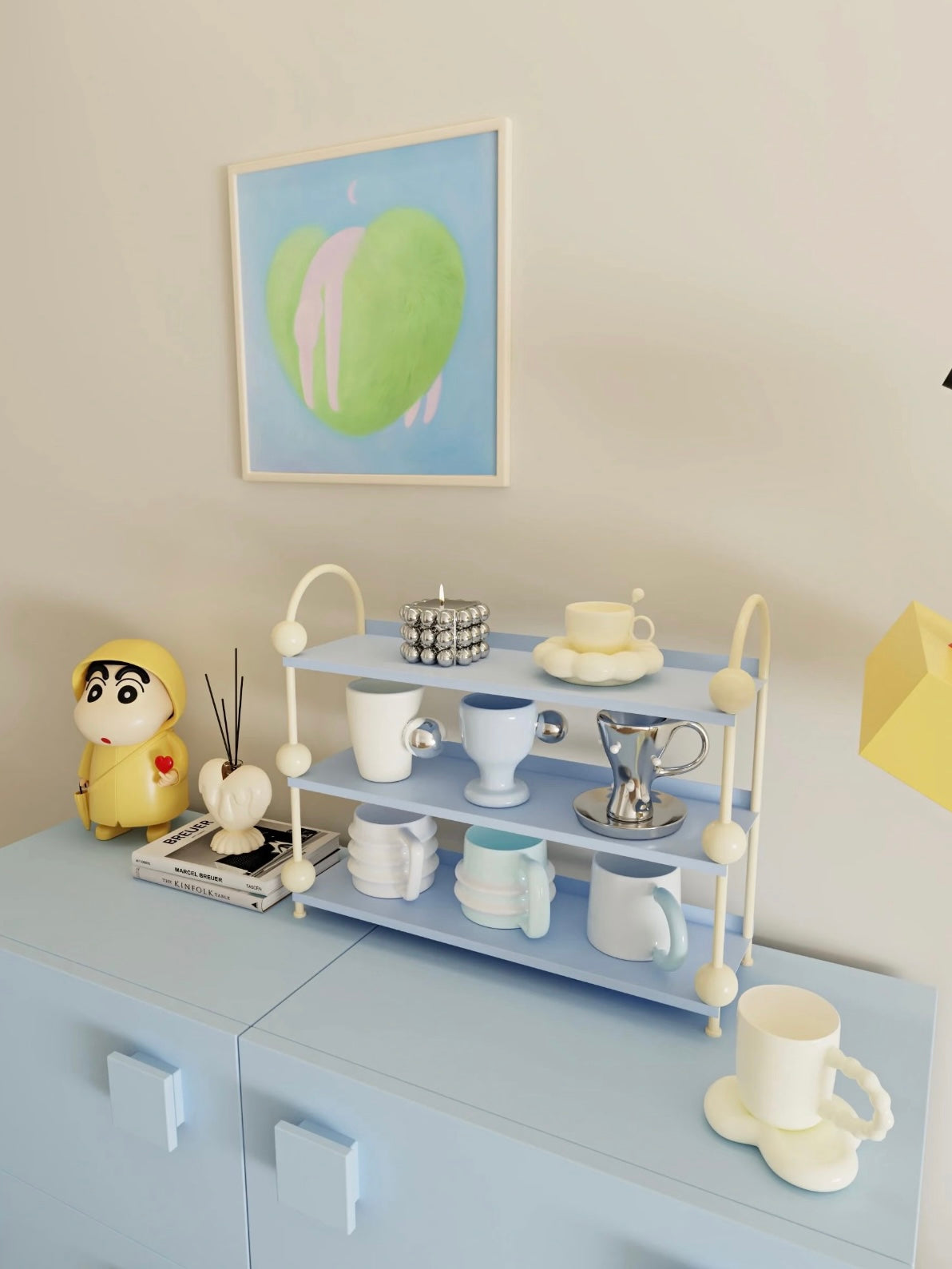 Blue tabletop shelf shown at an angle with cream ball details and cups and saucers on the open tiers.