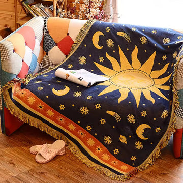 Decorative blanket with sun and moon design draped over a couch.