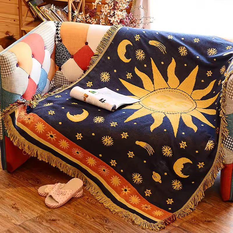 Decorative blanket with sun and moon design draped over a couch.