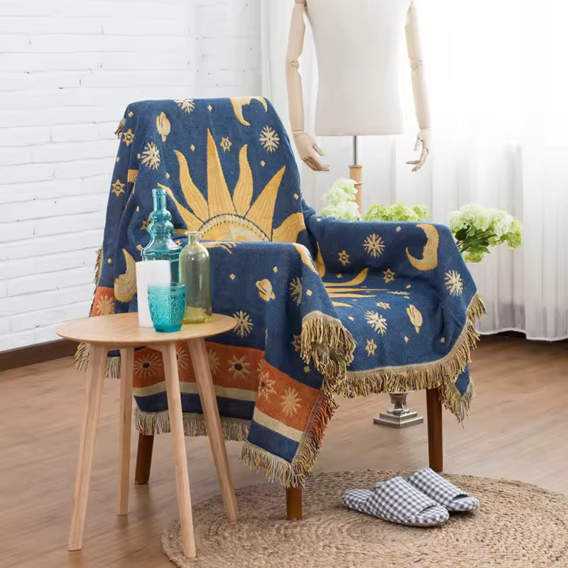 Decorative blue blanket with celestial design draped over a chair in a room with a table and plants.