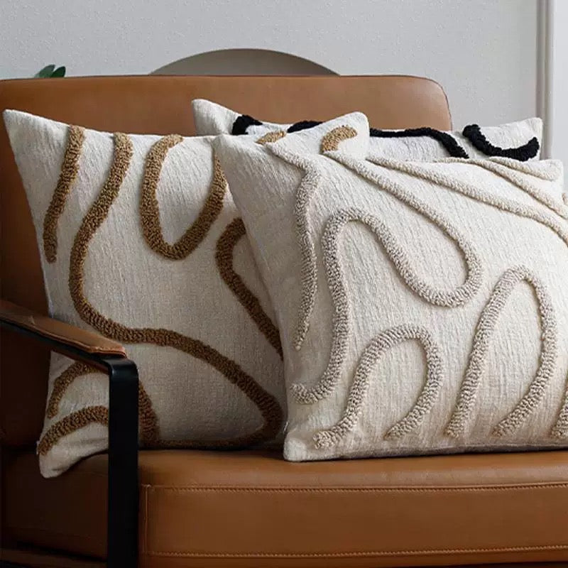 Decorative pillows with intricate patterns on a brown leather couch.