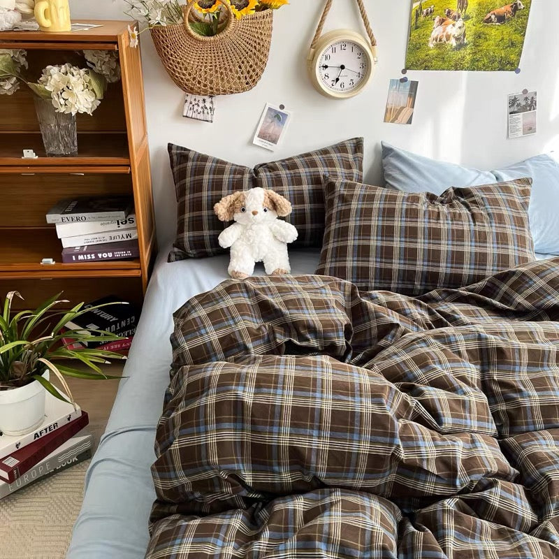 Bed with plaid bedding and pillows, surrounded by books and decor items.