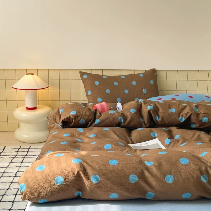 Warm brown polka dot duvet cover displayed on bed in calm college dorm interior