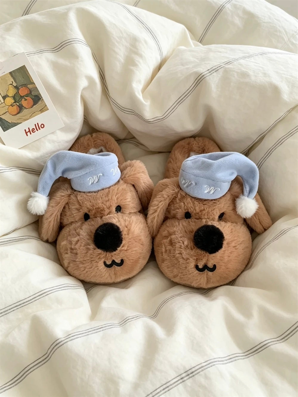 Brown plush puppy slippers placed on light bedding