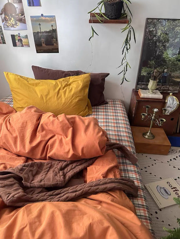 Burnt orange bedding set with mustard pillow, wall prints, and warm earthy bedroom decor.