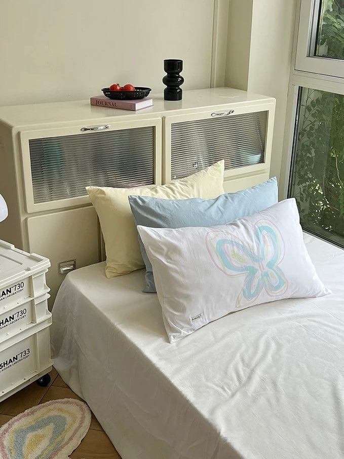 Butterfly print pillowcase displayed in a light bedroom with blue and yellow bedding.