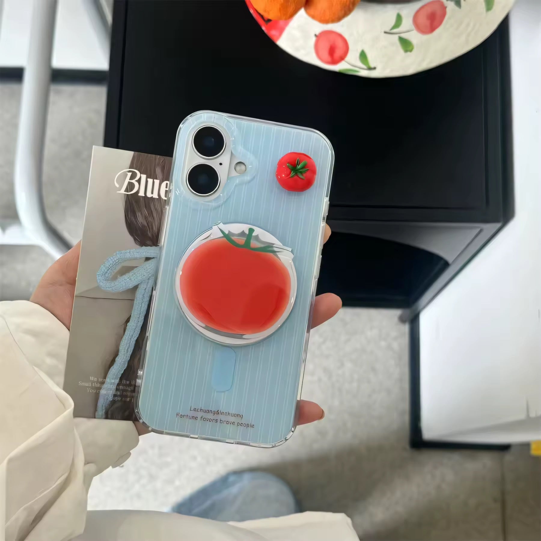 Vibrant fruit iPhone case with red 3D tomato on soft blue.