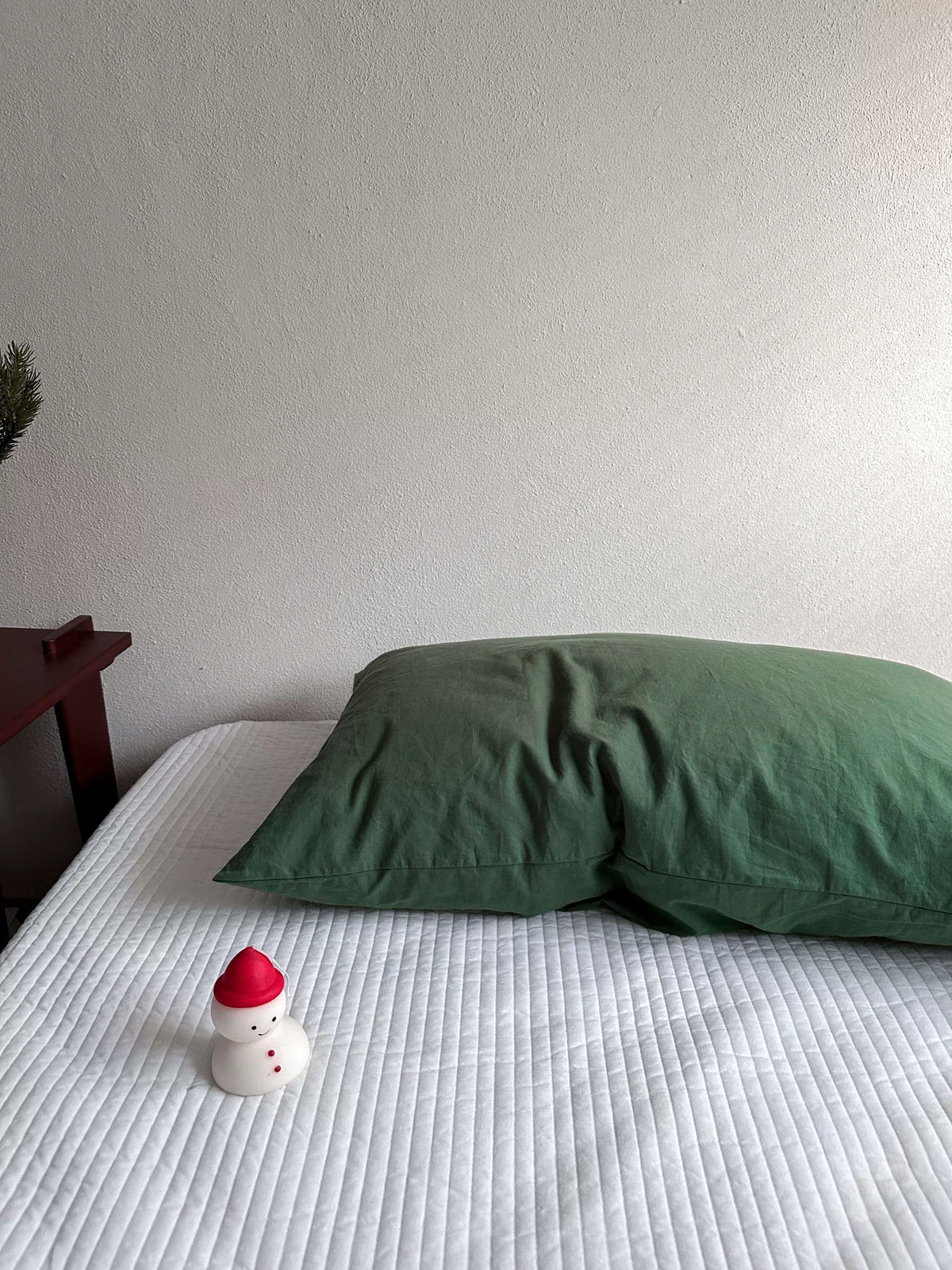 A cedar green pillowcase lies on its own in a solid muted shade.
