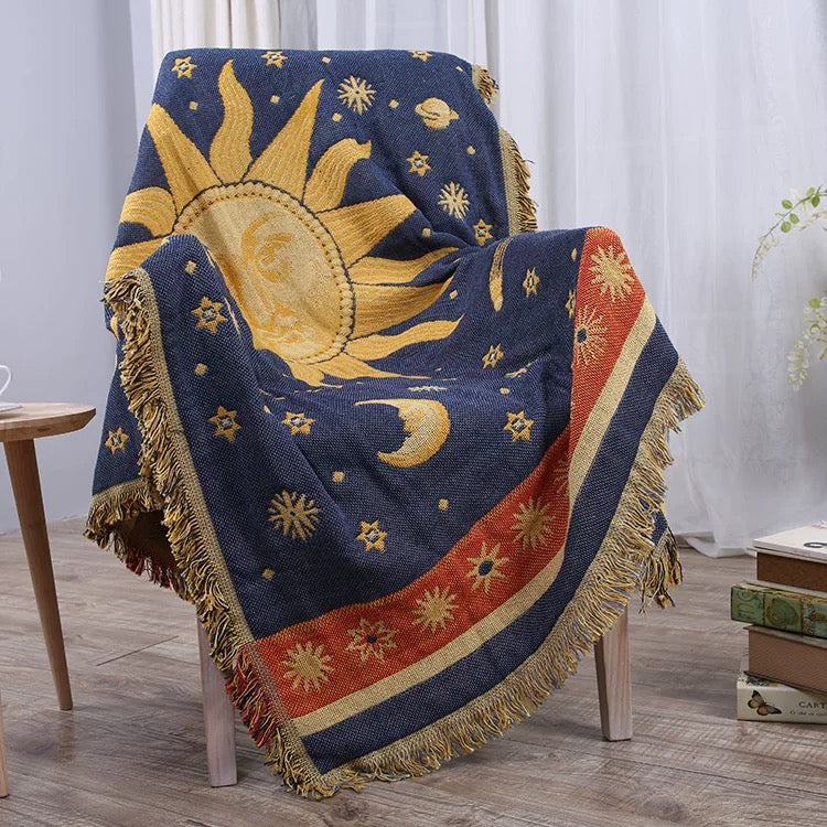 Decorative blanket with celestial design draped over a chair in a room.