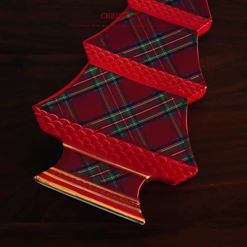 A close view of the ceramic Christmas tree shows its lower plaid tiers, red scalloped edges and gold base trim.