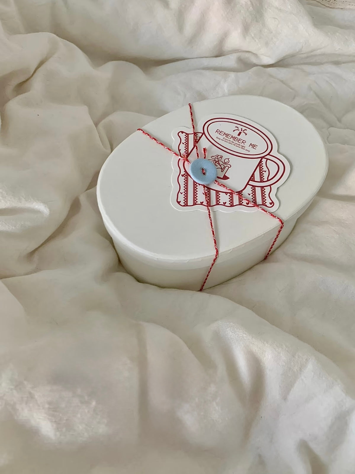 Cream Christmas candle gift box styled on soft bedding