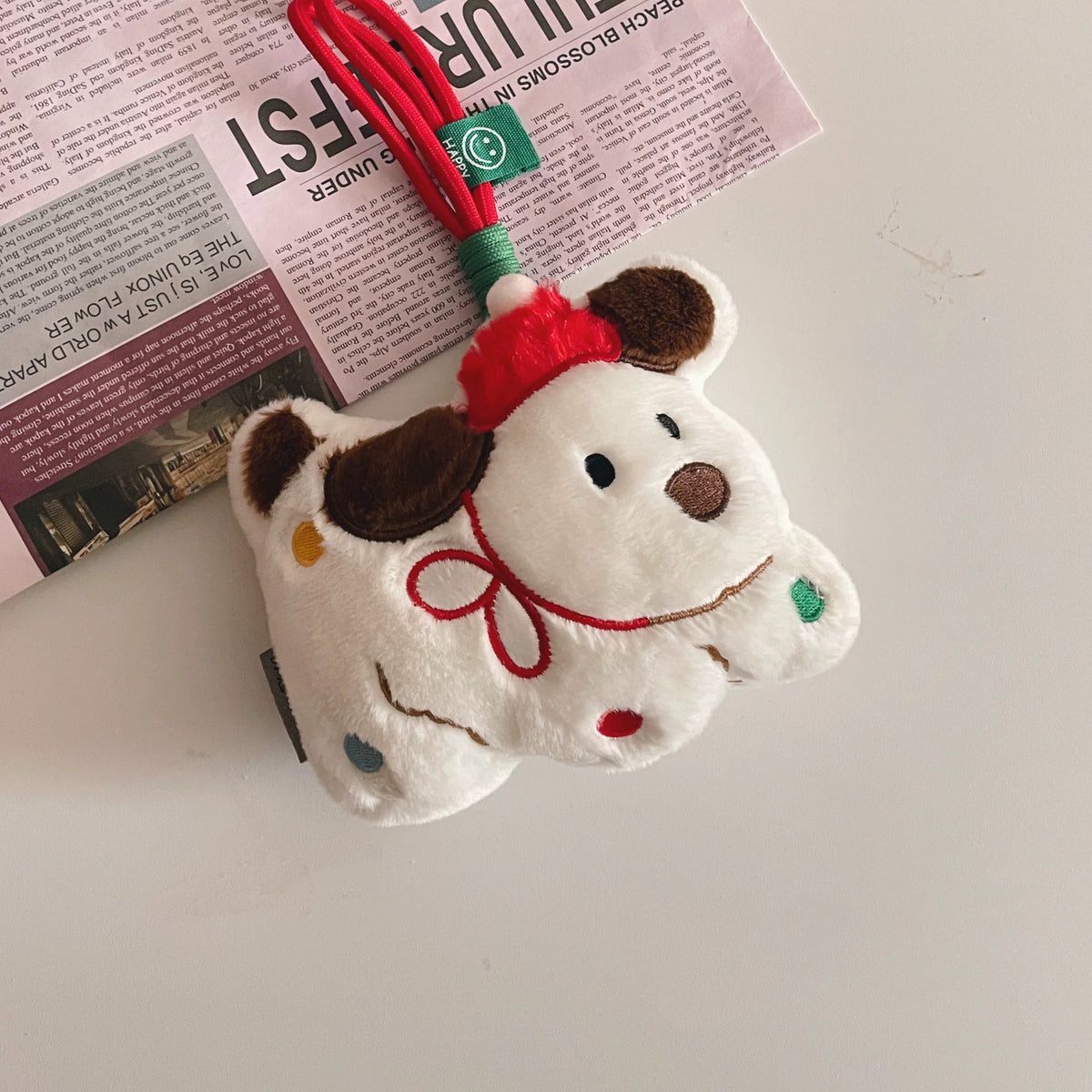 Christmas dog plush keychain with red hat and hanging loop on a tabletop