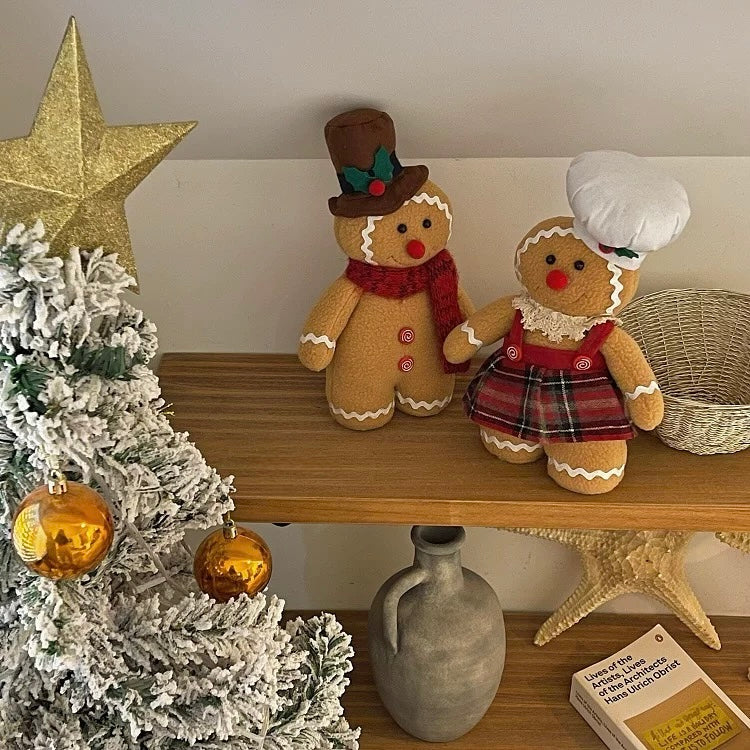 A Christmas gingerbread couple stands together, with a red scarf on the man and a plaid skirt on the woman.