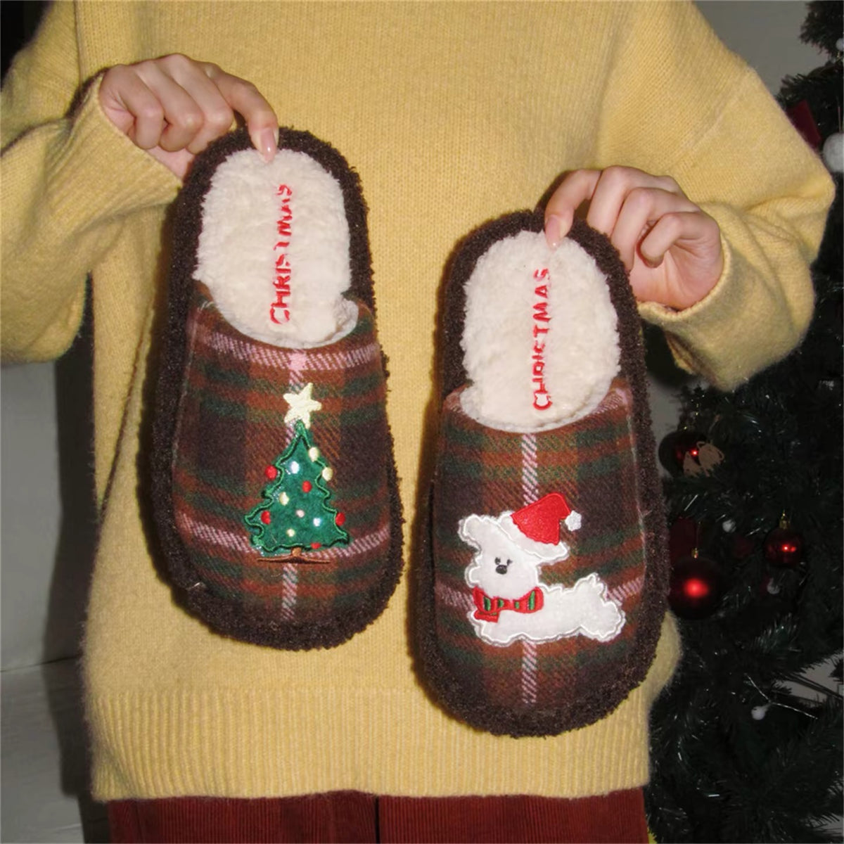Brown Christmas puppy house slippers held against a yellow sweater