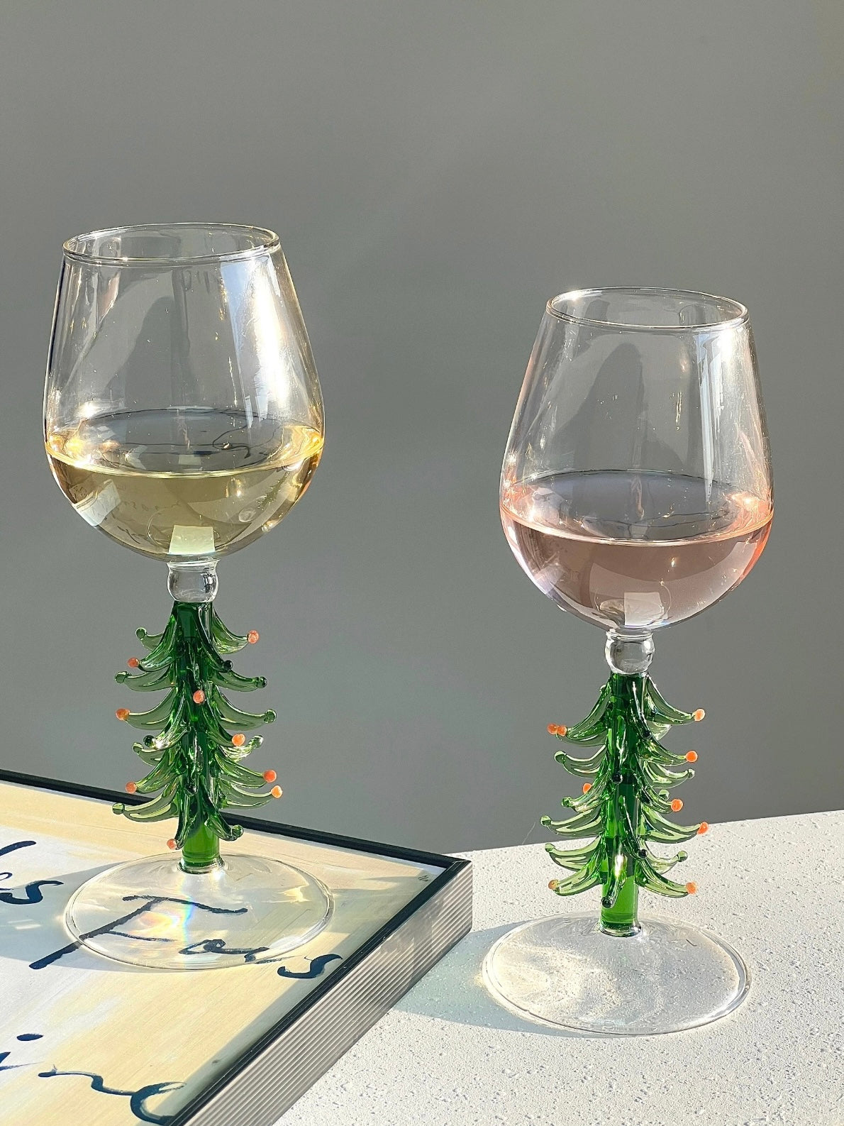 Holiday wine glasses with green Christmas tree stems styled near shelves