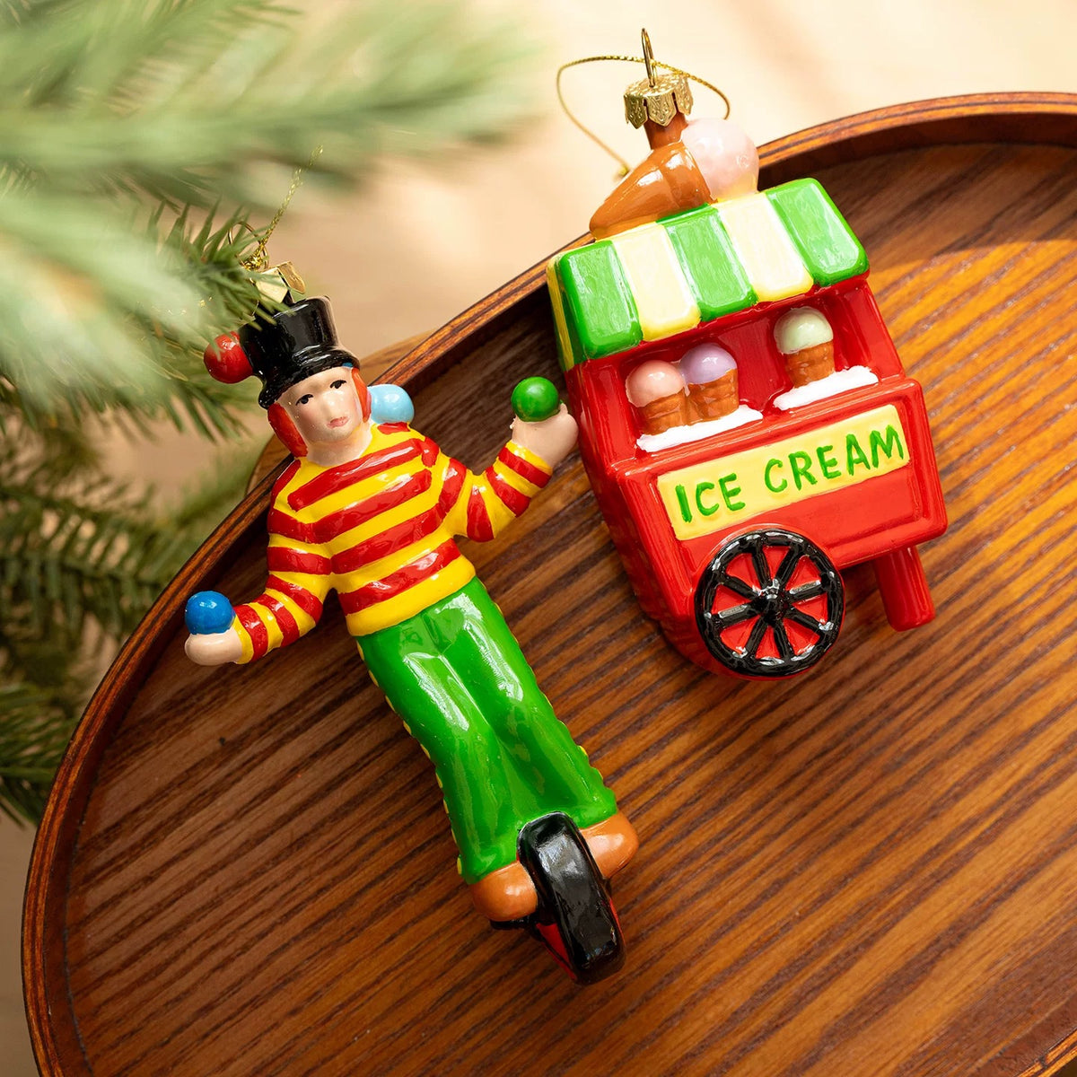 Circus ornaments show a clown on a unicycle beside a red ice cream cart with a green striped awning.