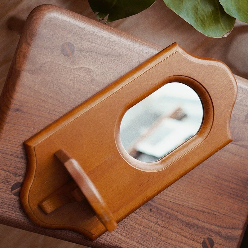 Wooden phone stand with mirror on a wooden surface