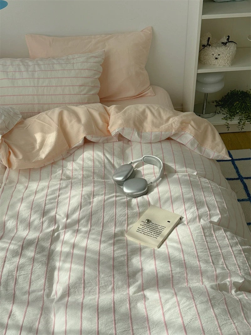Bed with peach-colored bedding and a heart-shaped object on a white sheet.