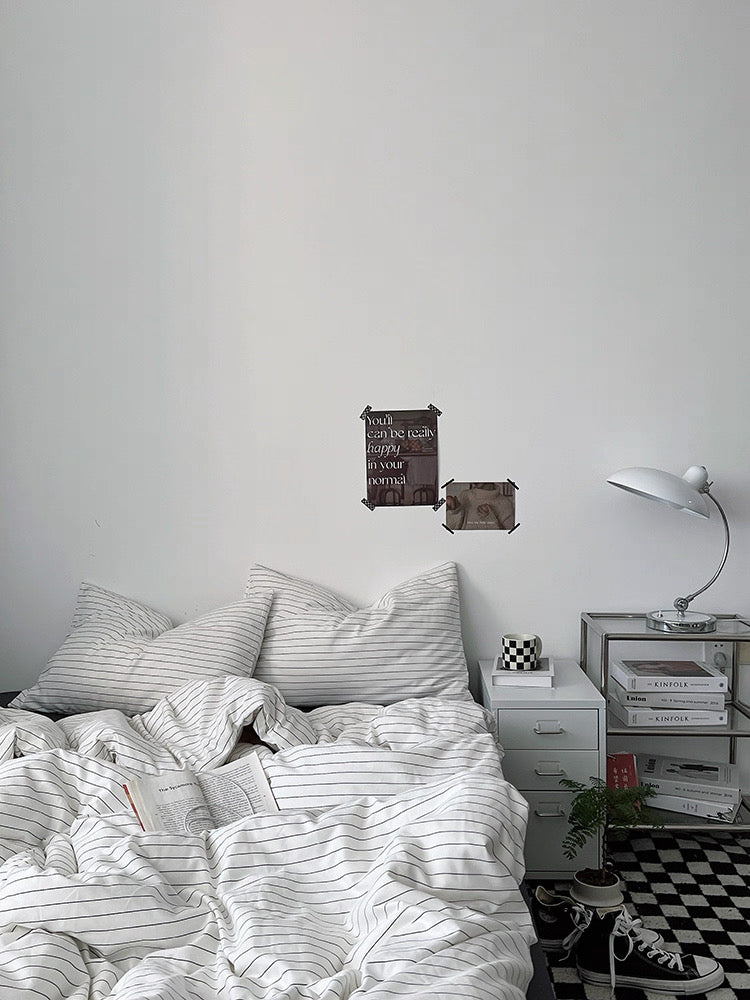 Bedroom with striped bedding, nightstand, and wall art.