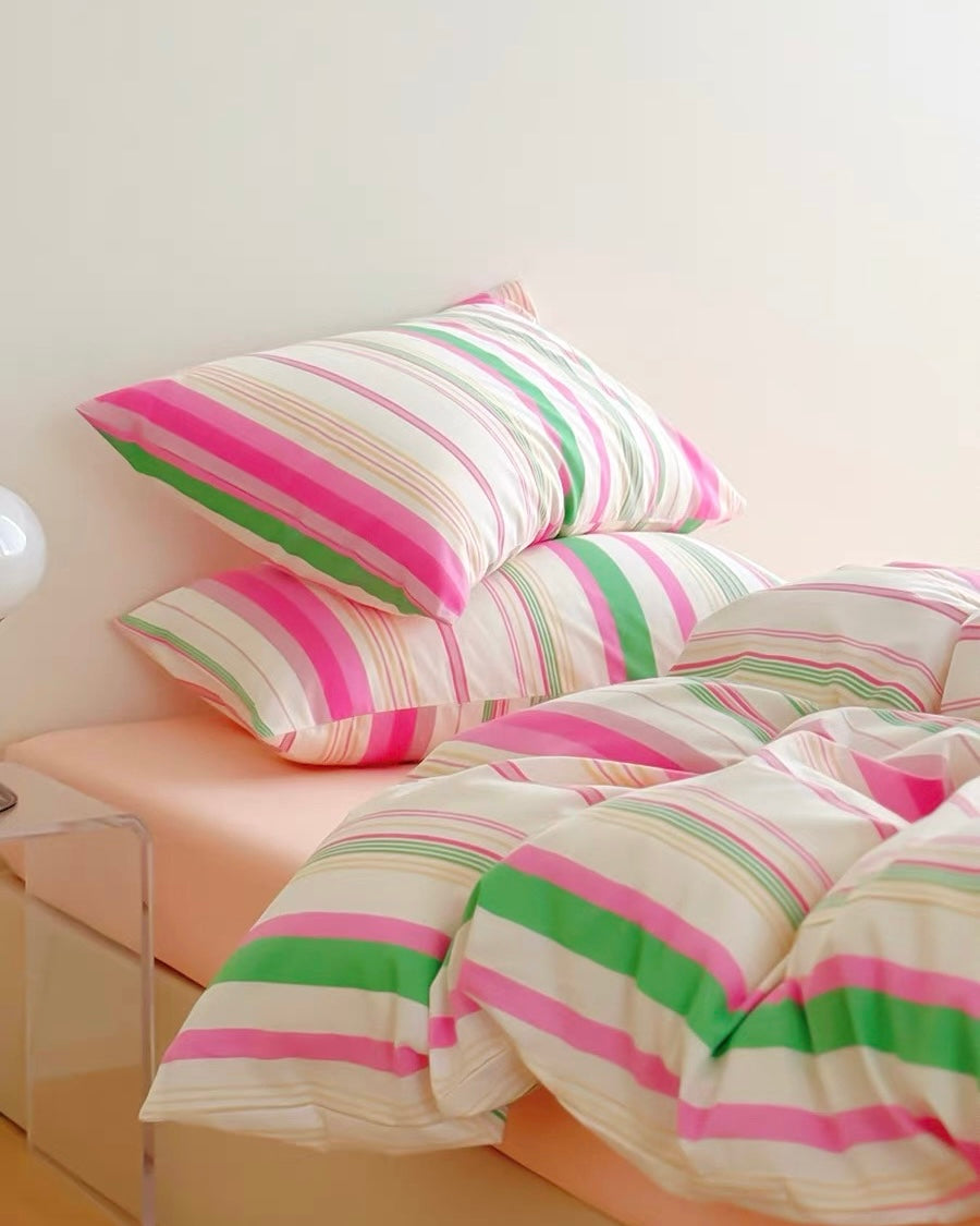 Striped bedding with pink and green lines on a bed with a white background