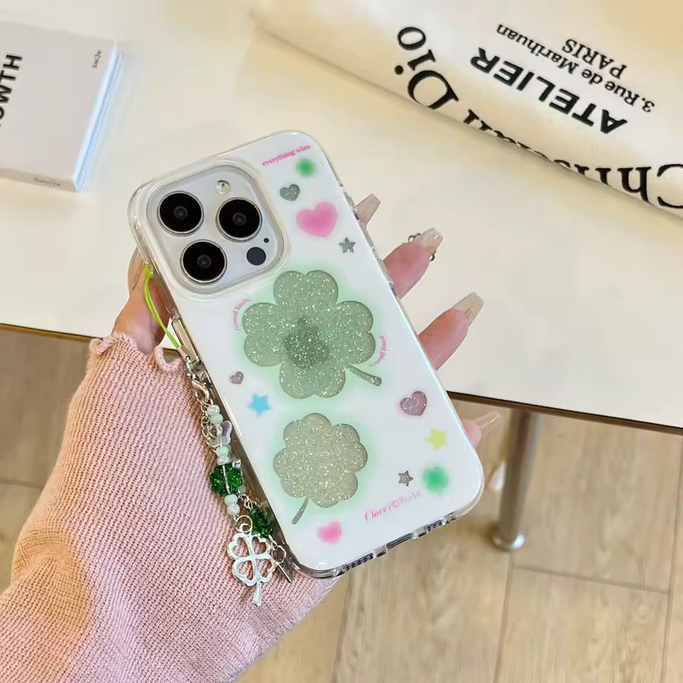 Phone case with clover design held by a hand on a wooden surface