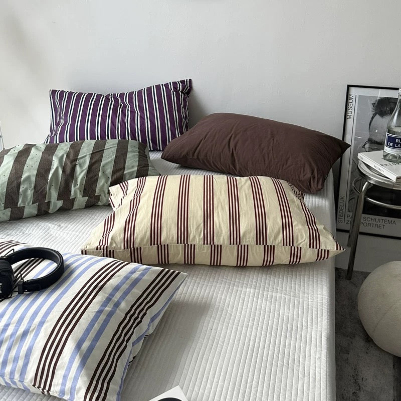 Bed with striped pillows and a nightstand in the background