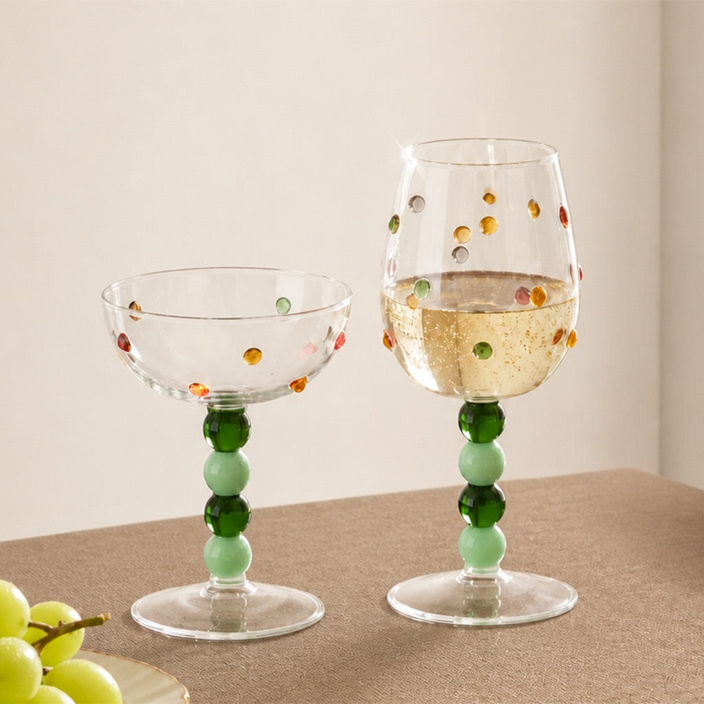 Colored stem wine glasses with raised polka dots in green on a tabletop