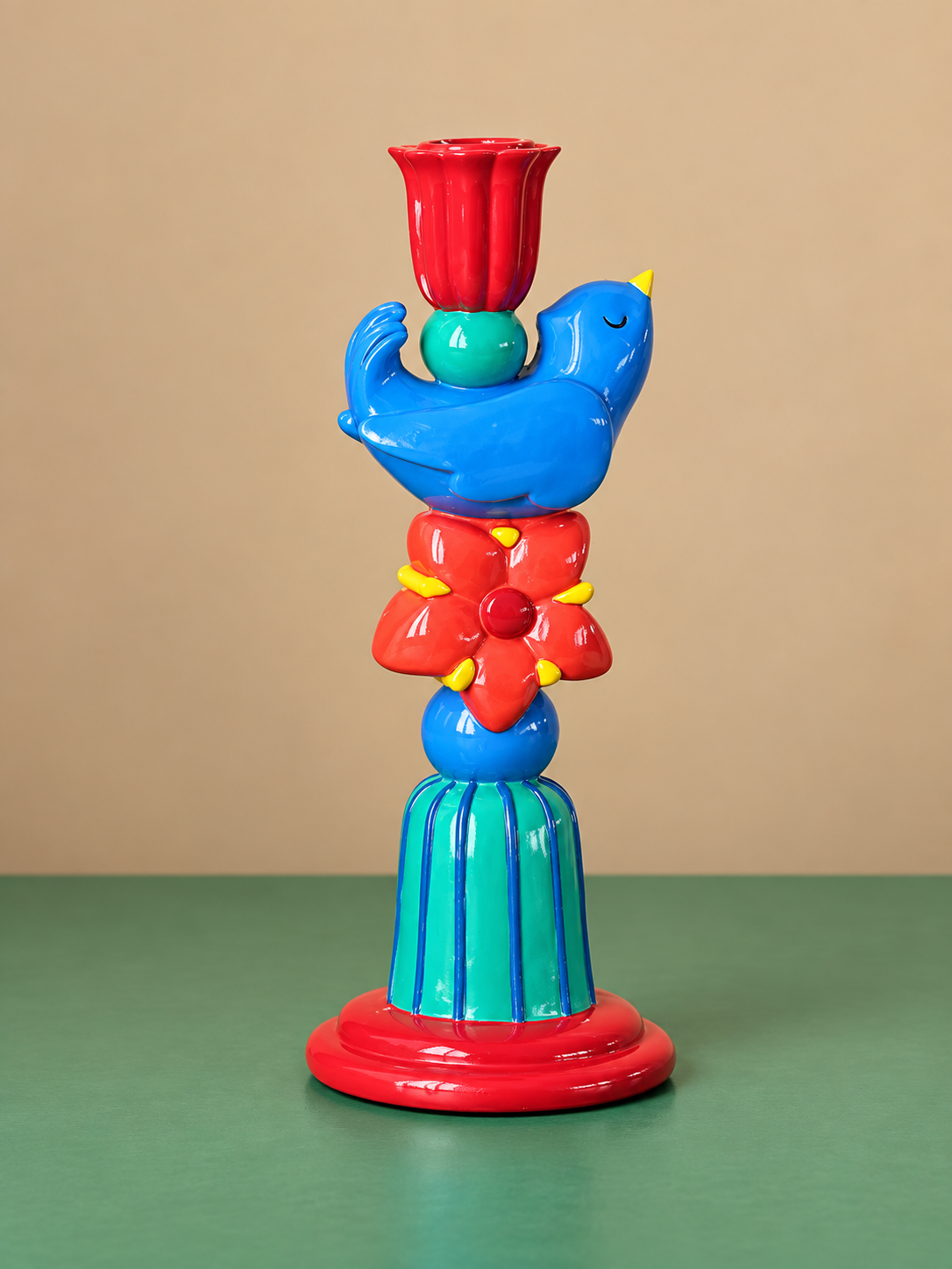 Blue bird candle holder with red flower detail, striped green pedestal, and red tulip-shaped candle cup.