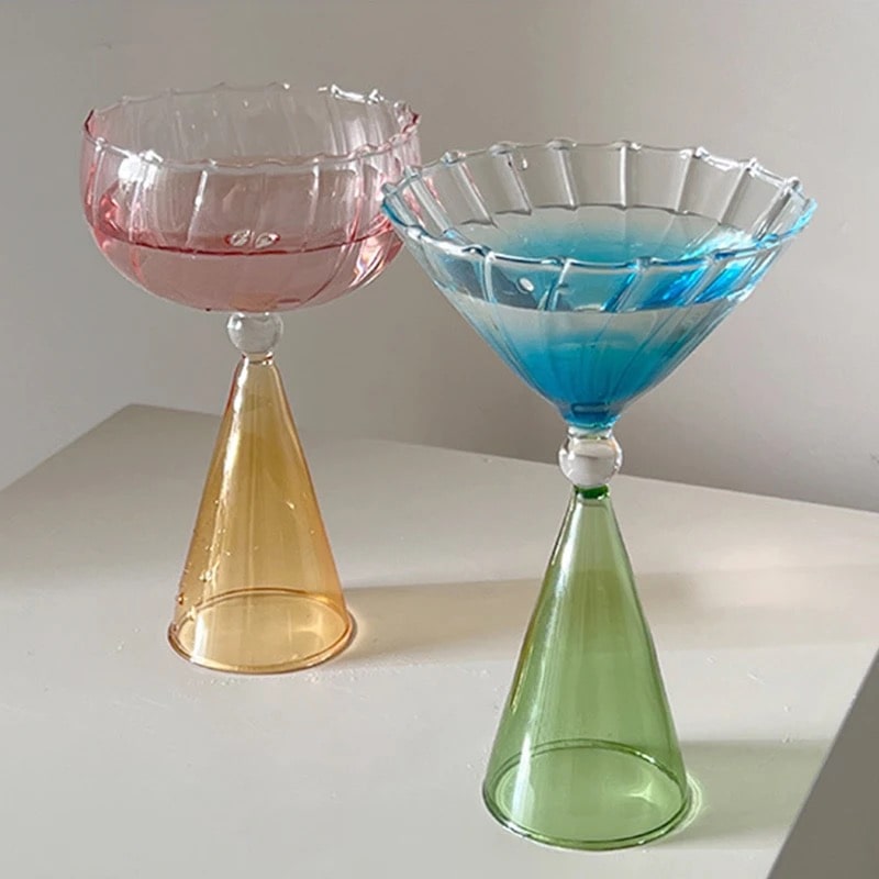Decorative stemmed cocktail glass with transparent bowl, pink accent, blue detail, and gold rim finish.
