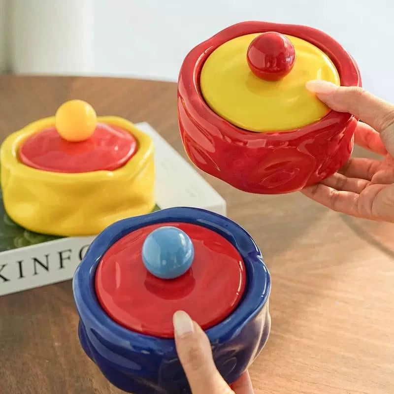 Colorful ceramic containers with lids on a wooden surface