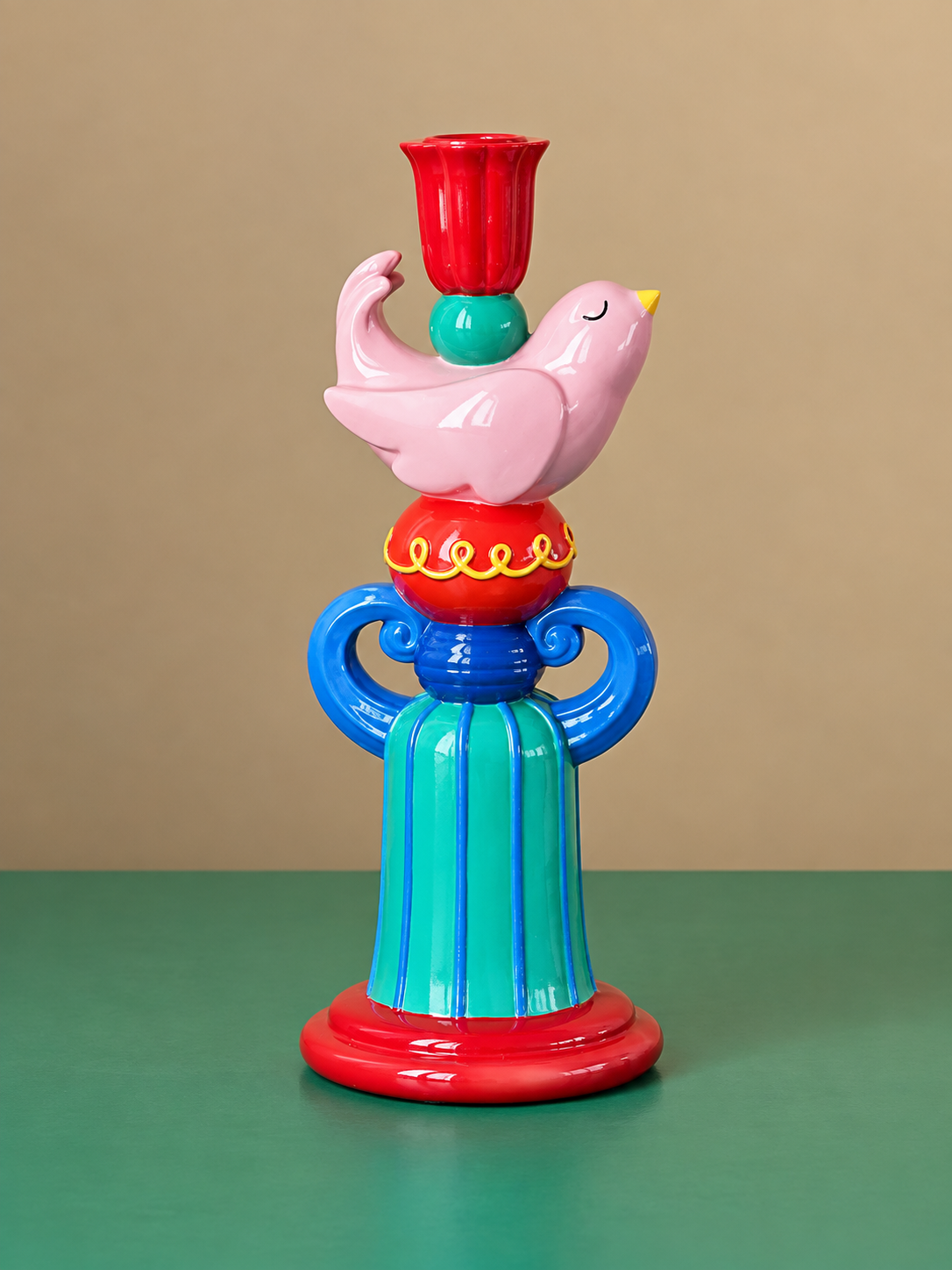Pink bird candle holder with blue scroll handles, striped green pedestal, and red tulip-shaped candle cup.