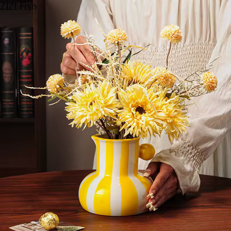 Yellow and white striped vase with flowers on a wooden table