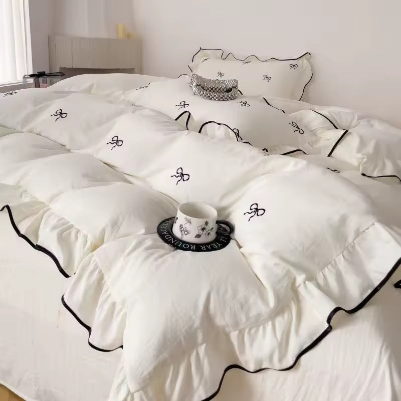 White coquette bedding set with embroidered black bows and frilled edges
