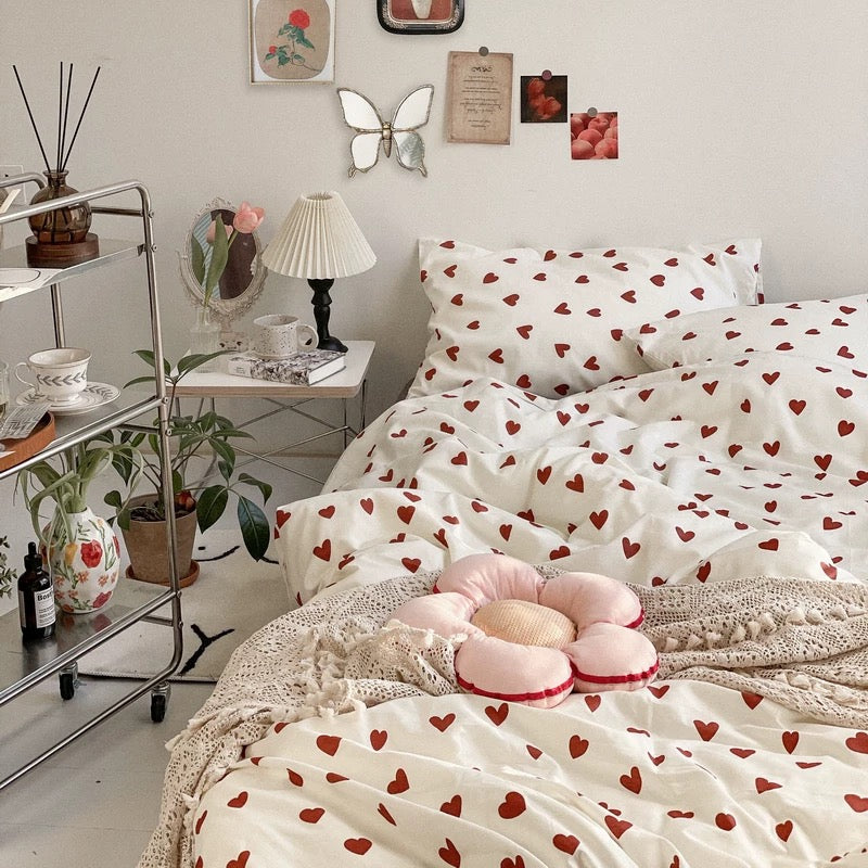 Coquette heart bedding styled in a bedroom with mirror, lamp, plants and pastel accents