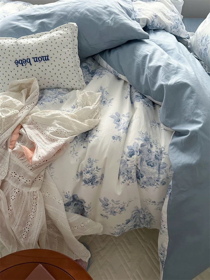 Blue floral ruffle cotton bedding set on a wooden bed frame with soft lighting.