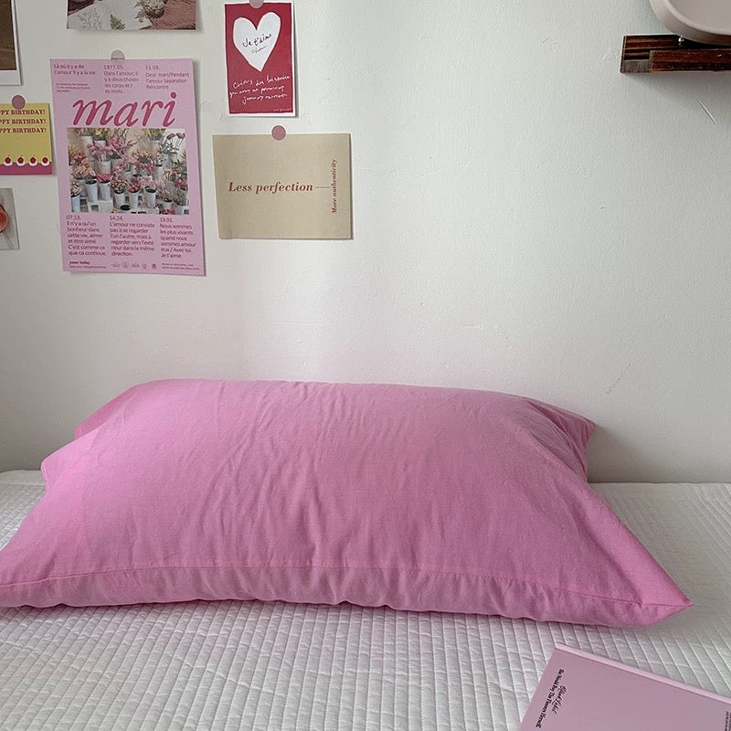 Pink pillow on a bed with posters on the wall