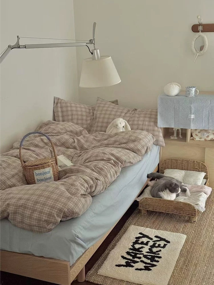 Cottagecore bedding seen from the side with a plain blue sheet beneath the light brown checked cover.