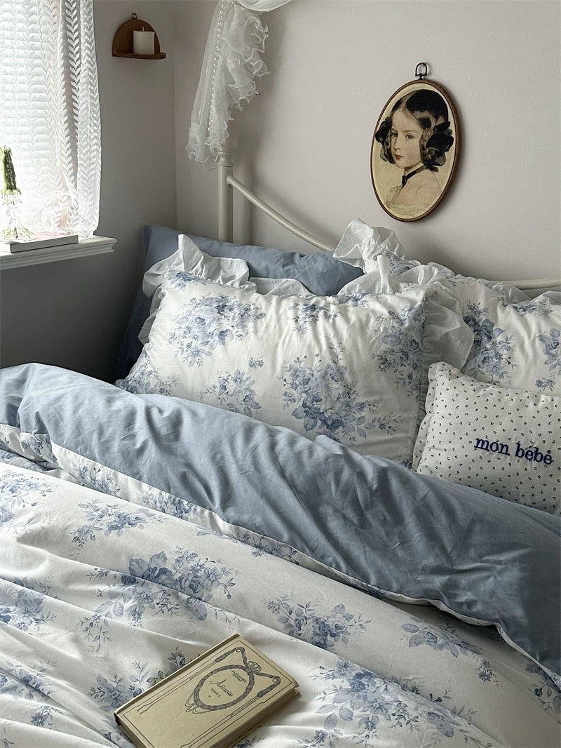 Vintage blue floral bedding styled with lace curtains and a dreamy atmosphere.