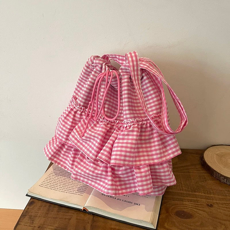 Pink gingham dress on a wooden surface with a book underneath
