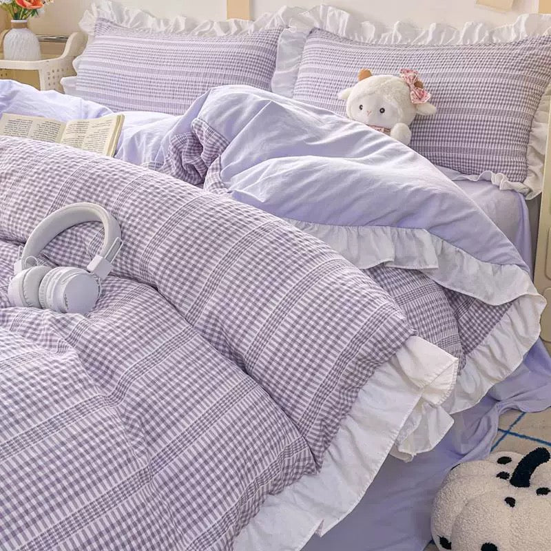 Purple checkered bedding set with ruffles on a bed, featuring a teddy bear and headphones.