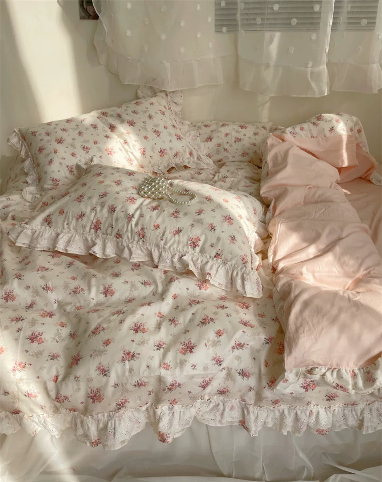 Close-up of pink embroidered flowers and lace trim on cotton duvet cover.